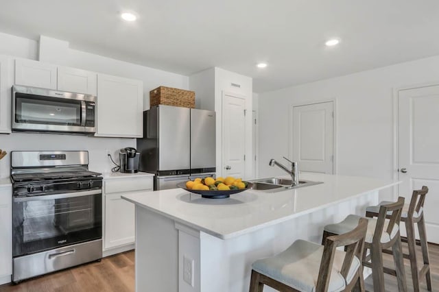 kitchen featuring a breakfast bar area, a sink, light countertops, appliances with stainless steel finishes, and white cabinetry