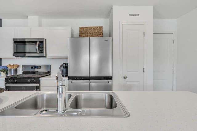 kitchen with appliances with stainless steel finishes, light countertops, and white cabinetry