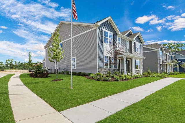 view of front of home featuring a front yard, stone siding, and a residential view