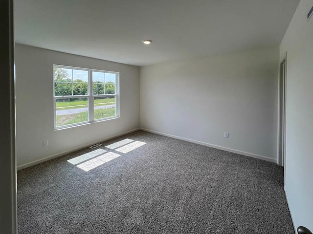 carpeted spare room featuring visible vents and baseboards