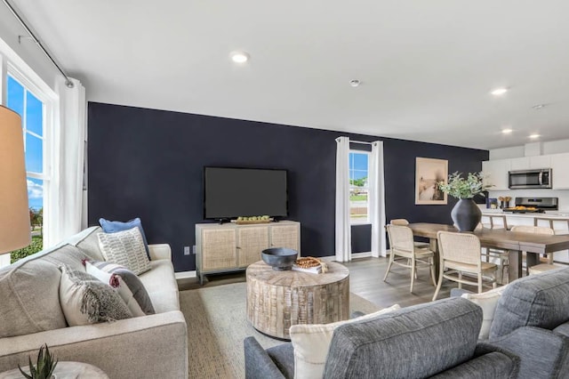 living room featuring recessed lighting, baseboards, wood finished floors, and an accent wall