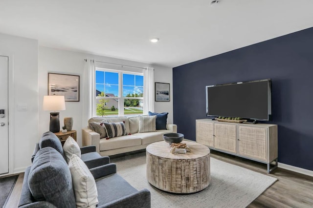 living area featuring an accent wall, wood finished floors, and baseboards