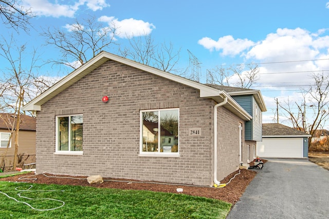 view of side of home featuring a detached garage, brick siding, and an outdoor structure