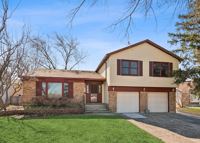 tri-level home featuring a front yard, a garage, brick siding, and driveway