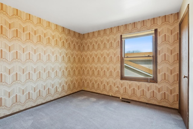 spare room featuring visible vents, carpet, and wallpapered walls