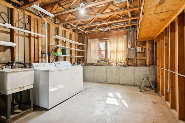 basement with a sink, electric panel, and washing machine and clothes dryer