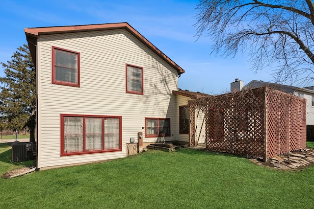 rear view of house featuring a lawn and central AC