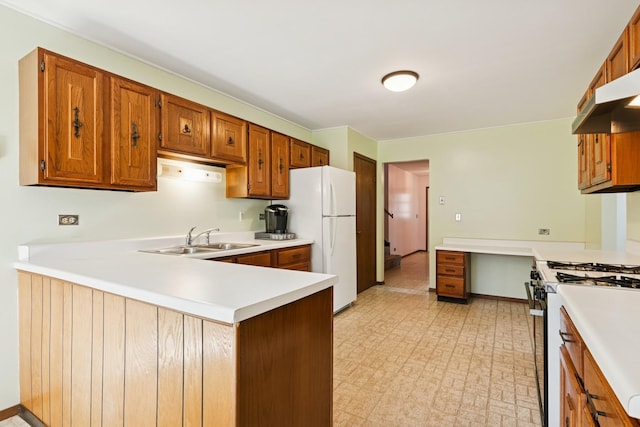 kitchen with light floors, light countertops, range with gas stovetop, freestanding refrigerator, and a sink