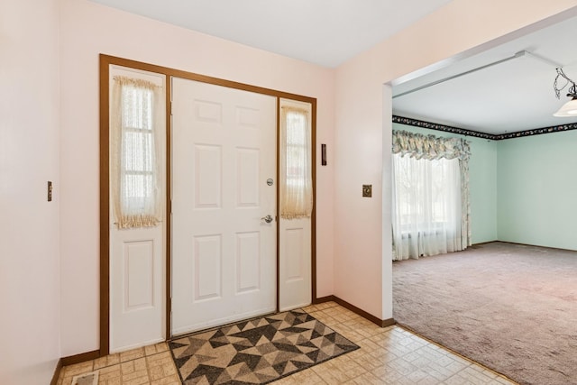 foyer entrance featuring light colored carpet, baseboards, and light floors