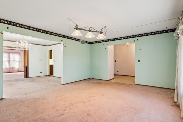 spare room featuring an inviting chandelier, carpet flooring, baseboards, and visible vents