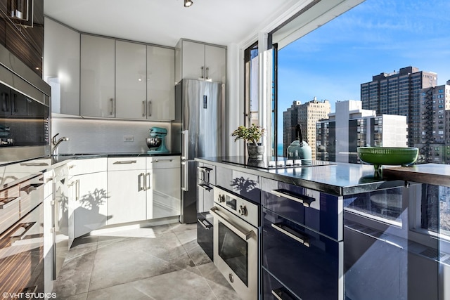 kitchen with a view of city, modern cabinets, gray cabinets, appliances with stainless steel finishes, and decorative backsplash