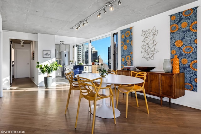 dining area with a city view, track lighting, baseboards, and wood finished floors