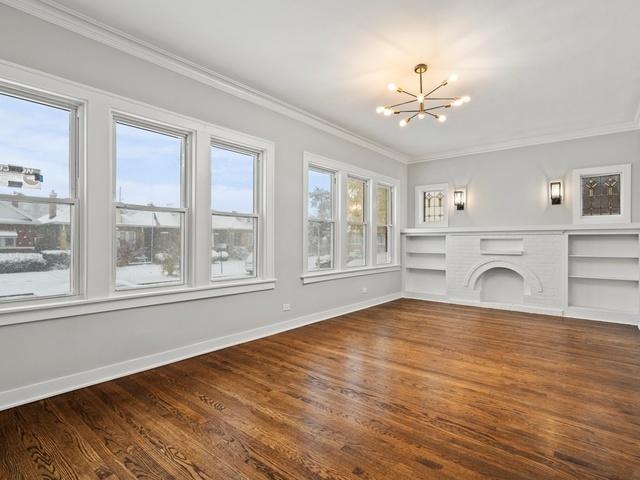 unfurnished living room with a chandelier, wood finished floors, and ornamental molding