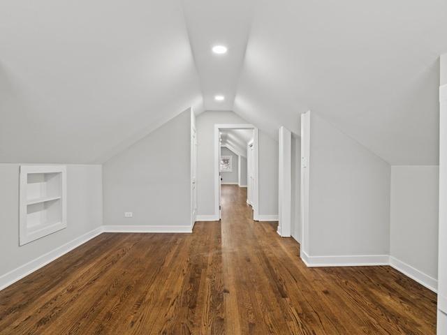 additional living space with lofted ceiling, built in features, dark wood-style floors, and baseboards