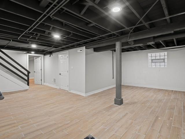 finished below grade area featuring stairway, baseboards, and wood finished floors