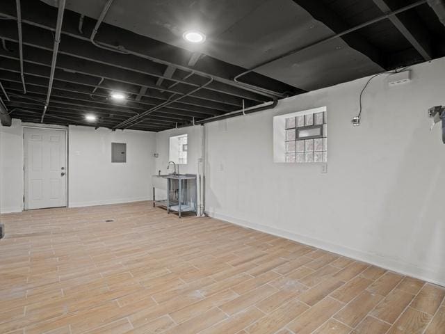 basement featuring electric panel, wood finished floors, and baseboards