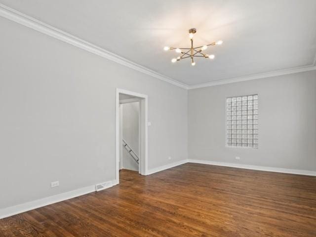 empty room with dark wood finished floors, baseboards, crown molding, and an inviting chandelier