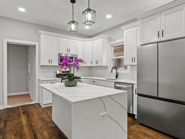 kitchen featuring a kitchen island, dark wood-type flooring, appliances with stainless steel finishes, white cabinets, and a sink