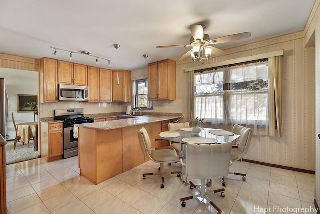 kitchen featuring wallpapered walls, baseboards, light tile patterned floors, appliances with stainless steel finishes, and a peninsula