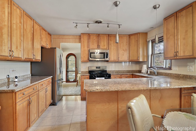 kitchen featuring a sink, a peninsula, light stone countertops, and stainless steel appliances