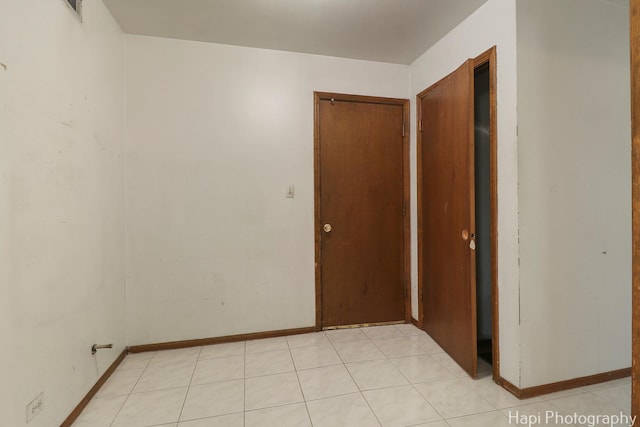 spare room featuring baseboards and light tile patterned flooring