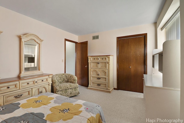 bedroom with visible vents, light colored carpet, and a closet