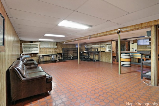 basement featuring tile patterned floors, a paneled ceiling, and wood walls