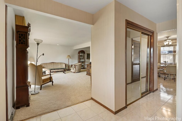 corridor featuring arched walkways, light colored carpet, light tile patterned flooring, and wallpapered walls