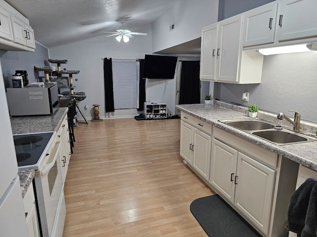 kitchen with lofted ceiling, light wood-style flooring, electric stove, white cabinets, and a sink