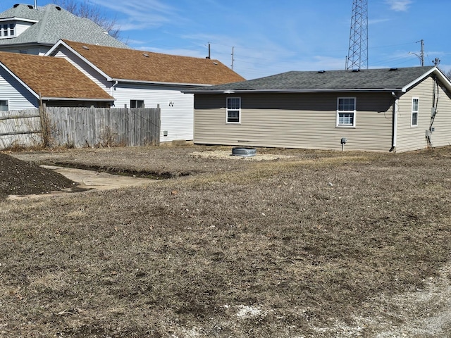 back of house featuring a shingled roof and fence