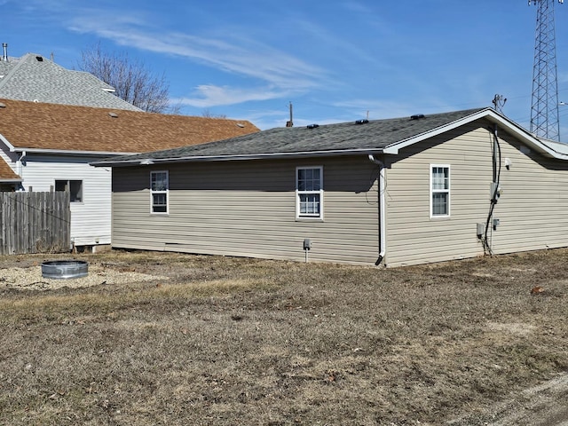 rear view of property featuring fence and roof with shingles