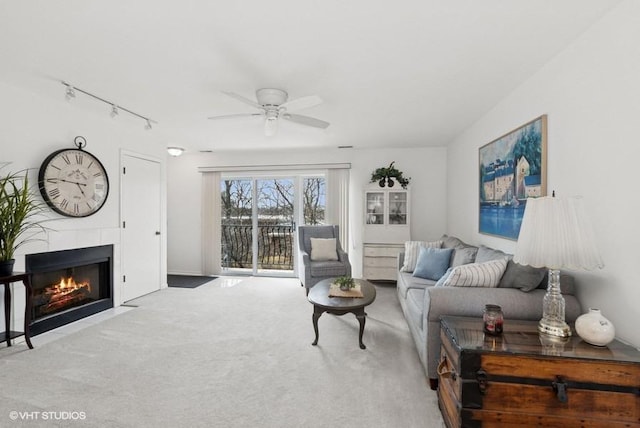 living area featuring carpet floors, ceiling fan, rail lighting, and a tile fireplace