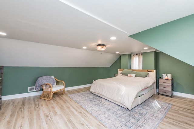 unfurnished bedroom featuring wood finished floors, baseboards, visible vents, recessed lighting, and vaulted ceiling