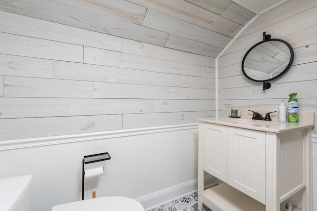 bathroom with vanity, toilet, lofted ceiling, and wooden walls