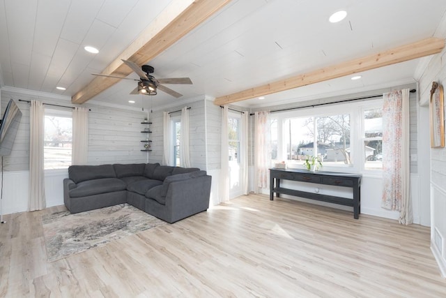 living area with beam ceiling, wood finished floors, and ornamental molding