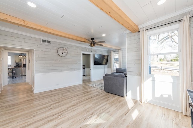 living area with beamed ceiling, plenty of natural light, visible vents, and light wood finished floors