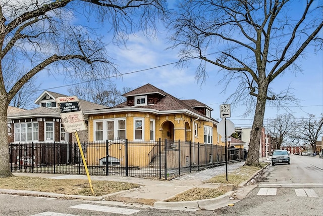 view of front of property featuring a fenced front yard, brick siding, and a shingled roof