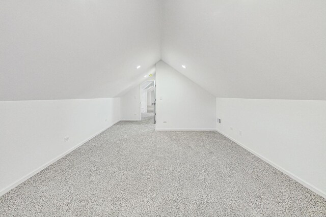 additional living space featuring light colored carpet, baseboards, and vaulted ceiling