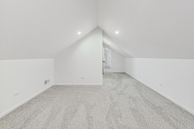 additional living space with baseboards, visible vents, lofted ceiling, recessed lighting, and light colored carpet