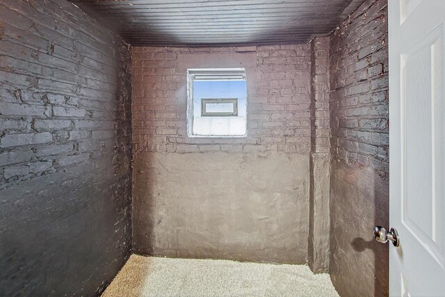 bathroom featuring wood ceiling and brick wall