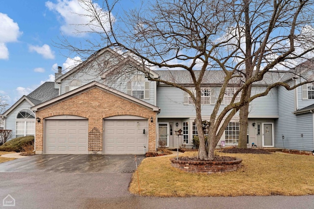 view of front facade featuring a front yard, an attached garage, a shingled roof, aphalt driveway, and brick siding