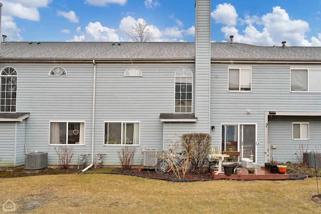 rear view of house with a patio area, central AC unit, a lawn, and a chimney