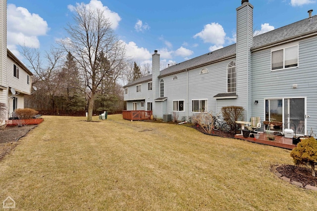 back of property featuring a wooden deck, central air condition unit, a yard, and a chimney