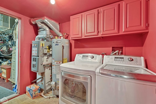 washroom featuring water heater, heating unit, independent washer and dryer, and cabinet space