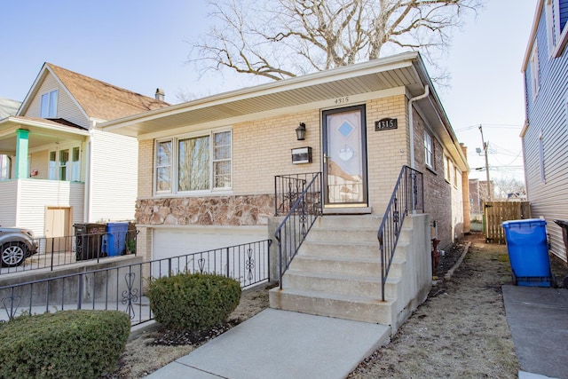 view of front of house with brick siding, an attached garage, and fence