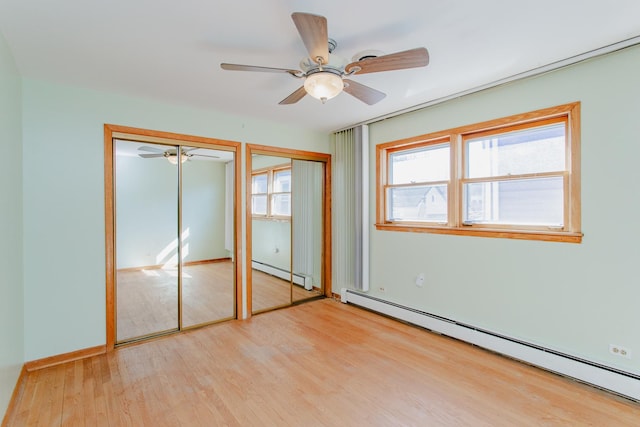 unfurnished bedroom with light wood finished floors, two closets, ceiling fan, and a baseboard radiator