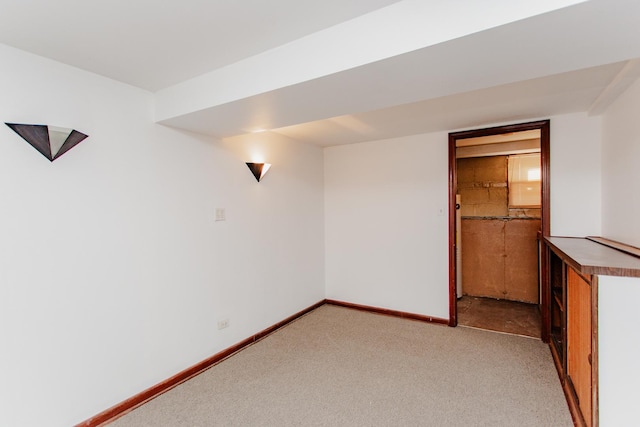 empty room featuring baseboards and light carpet