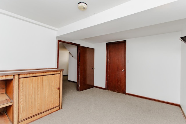 below grade area featuring light colored carpet and baseboards