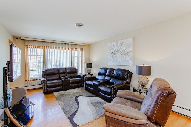 living room with a baseboard heating unit, wood finished floors, and visible vents