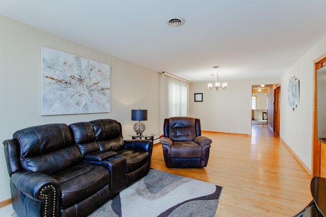 living area with baseboards, visible vents, light wood finished floors, plenty of natural light, and a notable chandelier